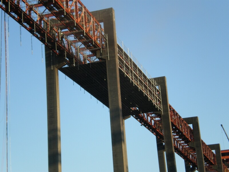Industrial scaffolding is seen wrapped around a bridge suspended high in the air. Working at such heights, safety is paramount and Scaffolding Solutions always puts safety first.