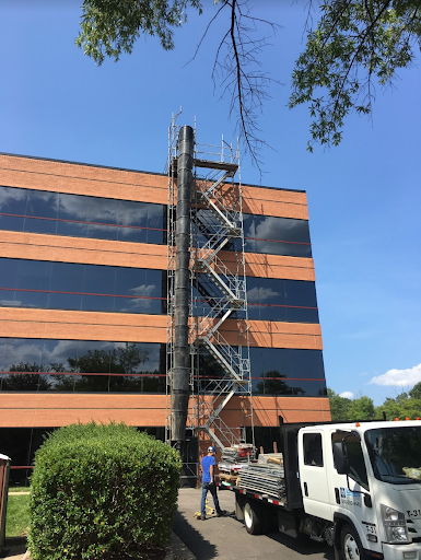 A black plastic construction trash chute attached to a building.